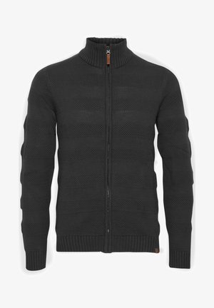 Svart zip-up genser med ribbestrikket høy krage, som har teksturerte horisontale striper og et koselig strikket materiale. Utsmykket med detaljer i brunt skinn.