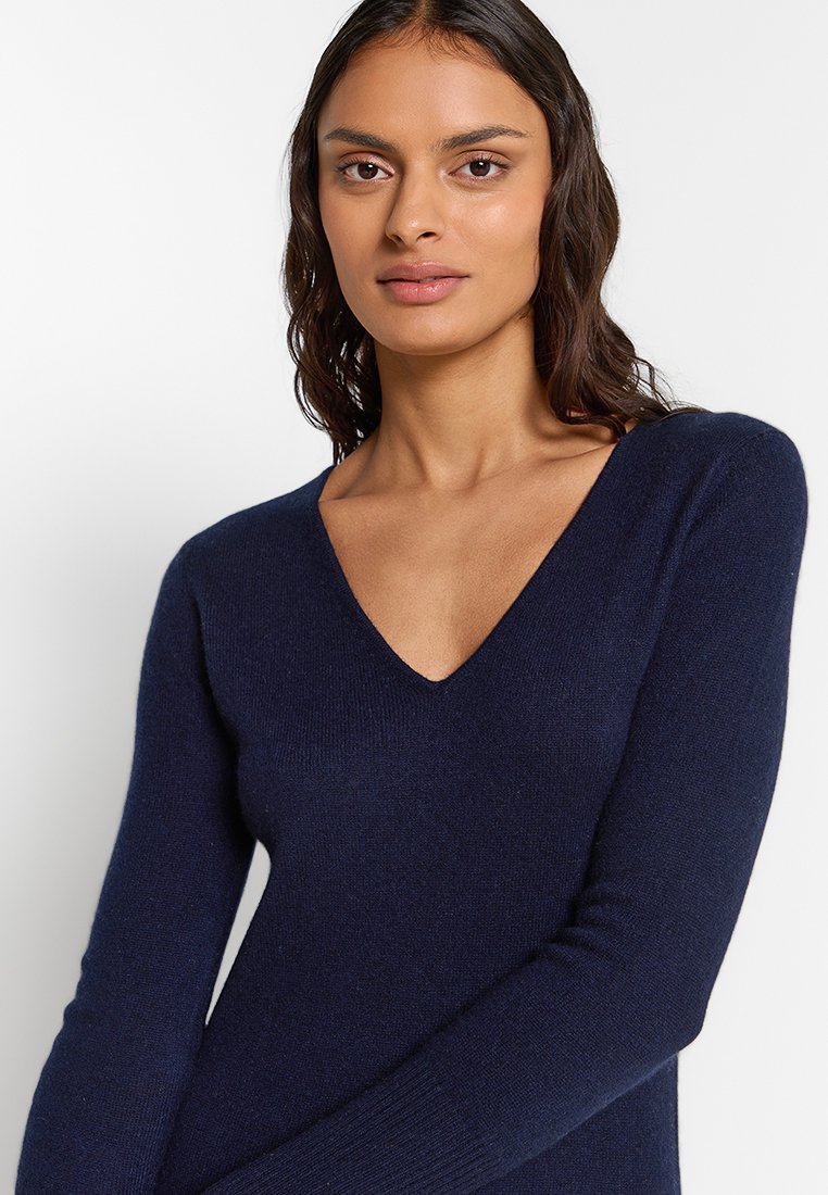 Marineblauer V-Ausschnitt-Pullover aus weichem Material mit langen Ärmeln und enganliegendem Schnitt, der eine glatte Textur und minimalistische Details aufweist.