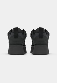 Kraftiga svarta skor med en strukturerad ovandel, utrustade med förstärkt hälstruktur och en bred, platt platå-sula. Bakre dragring ingår.