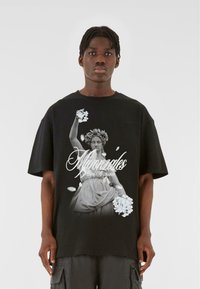 Sort T-shirt med et monokromt grafisk motiv af en klassisk statue, der holder blomster, med hvid tekst ovenpå. Korte ærmer og afslappet pasform.