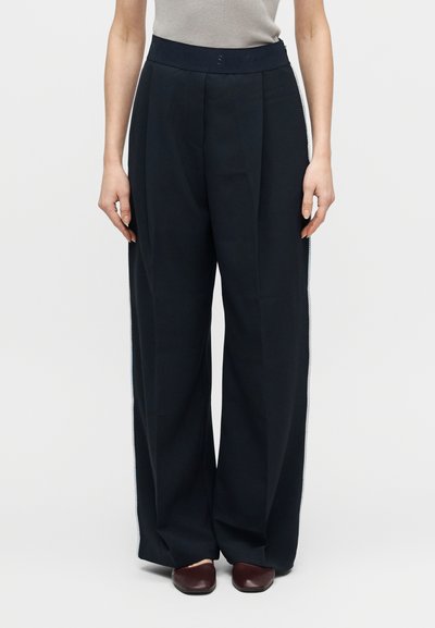 Pantalon à jambes larges en tissu bleu marine foncé, doté d'une taille haute, de plis subtils et d'accents latéraux avec une bordure verticale contrastante.