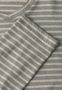 Bavlněné tričko s výstřihem do V, v krémové barvě s tmavě modrými vodorovnými pruhy. Měkká textura s pečlivě našitými lemy.