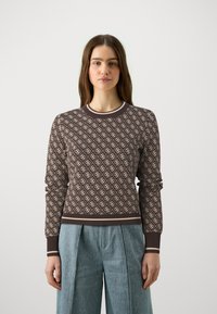 Brown patterned sweater with cream designs, ribbed crew neck, and cuffs. Paired with light blue wide-leg trousers.