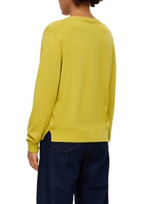 Gelber Strickpullover mit Rundhalsausschnitt, gerippten Bündchen und Saum. Die Rückansicht zeigt eine lockere Passform und eine glatte Textur. Kombiniert mit dunklem Denim.