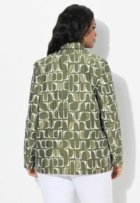 Chaqueta verde con estampado que presenta un diseño a cuadros con acentos en blanco. El material parece texturizado. La vista trasera muestra un corte entallado y un cuello estructurado.