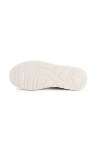 Sohle eines Sneakers, bestehend aus einem weißen Gummimaterial, strukturiert für besseren Grip, mit gemusterten Rillen und einem eingravierten Logo an der Seite.