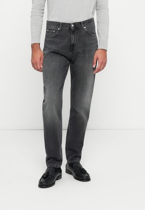 Grå denimjeans med rett passform, med fem lommer, knappestee, og subtile falming; brukt med svarte lærstøvler.