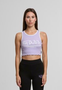 Ljuslila crop top med vit kant, med "Von Dutch" logo och "ORIGINALS" text i fet stil. Scalloped nederdel.