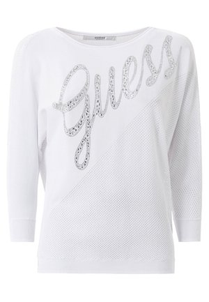 Weißer Pullover mit weitem Ausschnitt und drei Viertelärmeln, versehen mit einem silbernen Pailletten-"Guess"-Logo auf der Vorderseite und einem strukturierten Netzdesign.