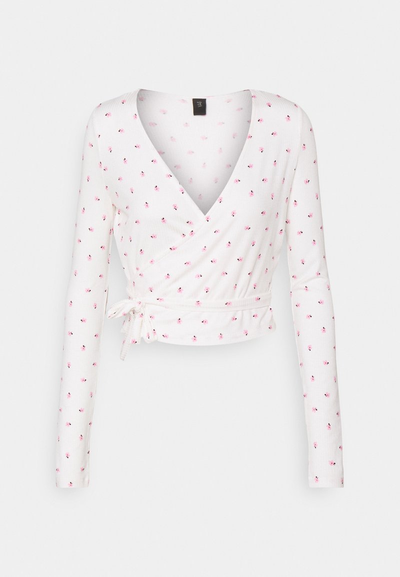 Bílý dlouhý rukávový zavinovací top s hlubokým V výstřihem, zdobený malým růžovým květinovým vzorem a vázáním v pase. Měkká, ribsovaná textura.