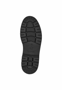 Musta kumipohja, jossa on teksturoitu pinta, erottuvat urat ja keskeinen logo. Suunniteltu pitävyyttä ja kestävyyttä varten.