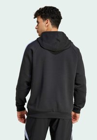 Sort hætte sweatshirt med en afslappet pasform, der har raglanærmer og en blød tekstur. Lyseblå sidestriber tilføjer kontrast.