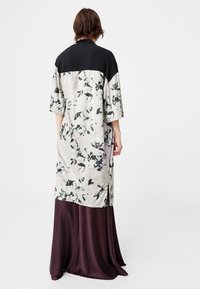 Sukienka w kwiaty z czarną górą, z krótkimi rękawami i długą, zwiewną bordową spódnicą. Gładka faktura z bocznymi rozporkami.