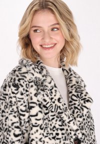 Palton din blană sintetică, cu imprimeu leopard alb-negru; are un guler cu tăietură, închidere cu nasture și un material moale, texturat.