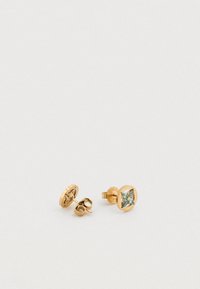 Στρογγυλά χρυσά σκουλαρίκια καρφάκια με ένα ανοιχτό μπλε πολύτιμο λίθο στο κέντρο, επιφάνεια με υφή και κούμπωμα με καρφί.