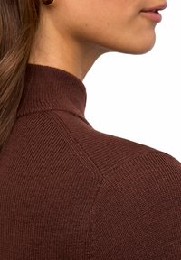 Brauner gerippter Strickpullover mit hohem Kragen, der ein strukturiertes Muster und Details an den Schultern aufweist, seitlich gezeigt ohne vollständige Ansicht.