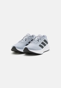 Light gray athletic shoes with a breathable mesh upper, black stripes, and a white midsole. Features a textured rubber outsole for grip.