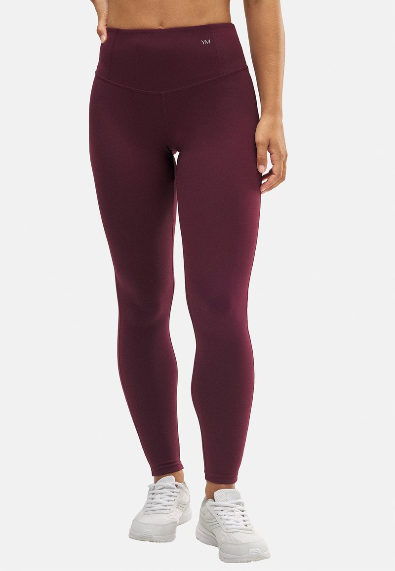 Mallas de tiro alto burdeos hechas de tela elástica. Presentan una textura suave y una mínima marca en la cinturilla.