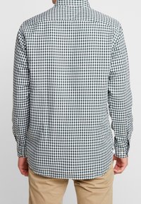 Camisa de manga larga a rayas verdes y blancas con cuello abotonado y dobladillo redondeado, hecha de una tela ligera, de ajuste estándar.