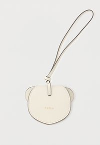 Κρέμα δερμάτινη θήκη καρτών σε σχήμα προσώπου αρκούδας, με μαύρες άκρες και λεπτό λουράκι. Εμπρός διακοσμημένο με την ένδειξη "FURLA" σε χρυσό.