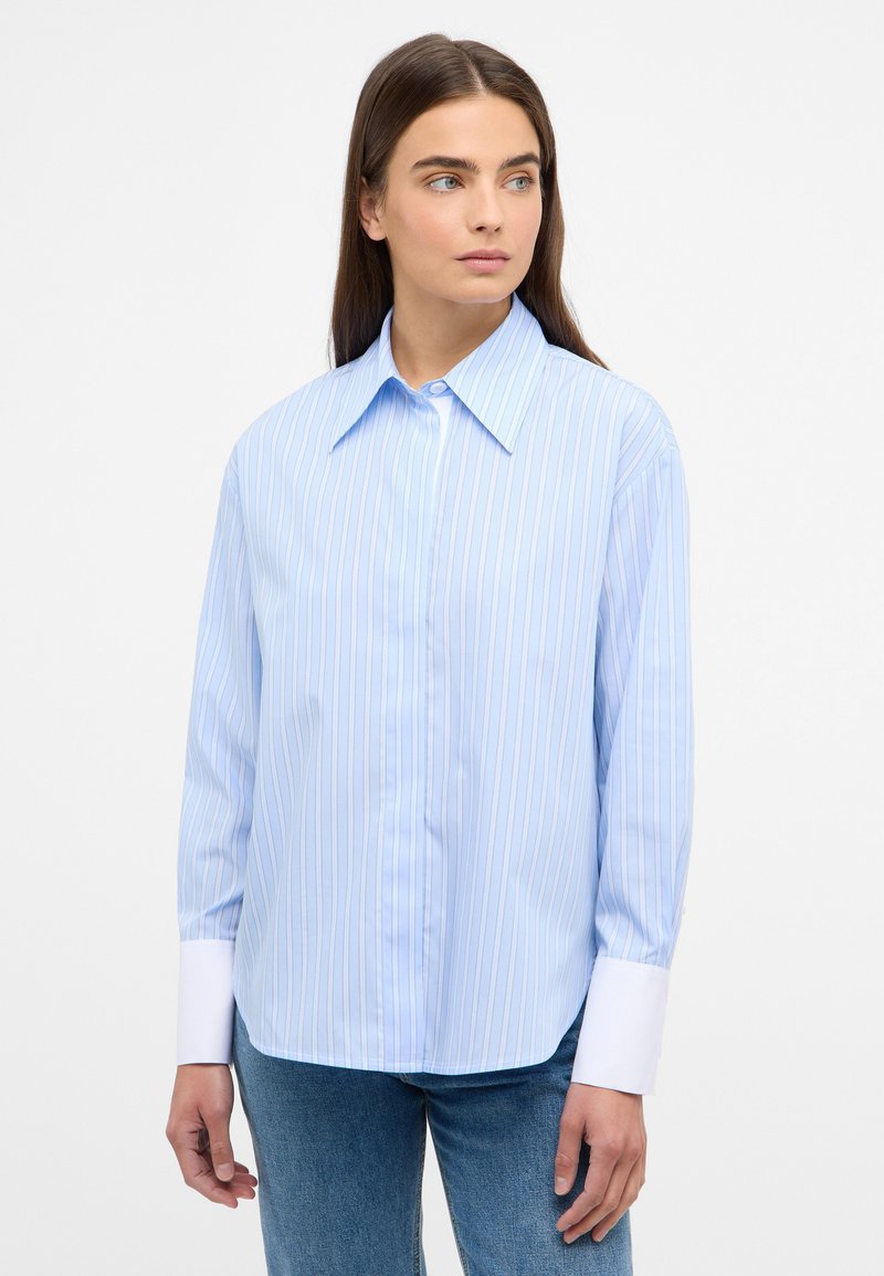 Light blue long-sleeve shirt with white vertical stripes, button-up front, large collar, and contrasting white cuffs, set against a plain background.