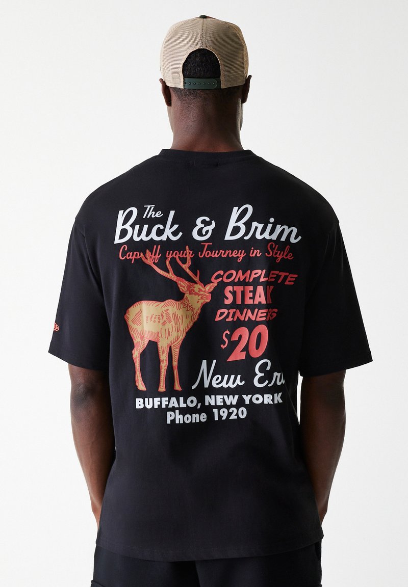 Μαύρη βαμβακερή μπλούζα με γραφικό σχέδιο που απεικονίζει έναν ελαφό, κείμενο σε κόκκινο και άσπρο. Κοντά μανίκια, χαλαρή εφαρμογή, απλή πλάτη, κανονικός λαιμός.