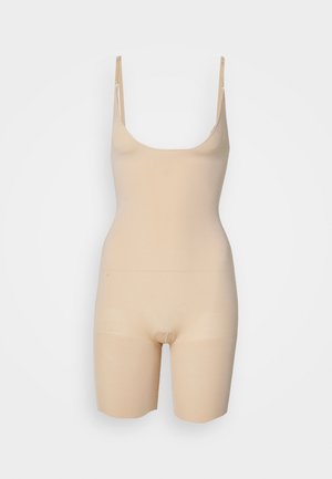 Nude seamless bodysuit with thin adjustable straps, a scoop neck, and mid-thigh length, made from stretchy, smooth fabric.