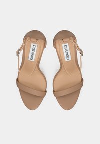 Beige avokkaat, joissa on sileä mattapinta, leveä etuosa ja nilkkahihna, jossa on hopeinen solki.