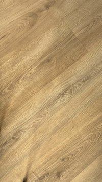 Un revêtement de sol en stratifié aspect bois de couleur beige clair avec une texture à grain naturel, présentant des nuances variées et des motifs organiques subtils sur la surface.