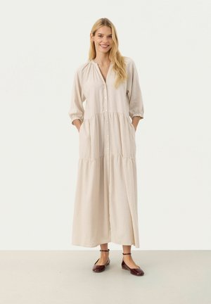 Light beige linen dress with a button front, gathered waistline, and three-quarter sleeves. Features side pockets and a flowy, maxi design.