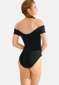 Maillot de bain noir décolleté, présentant un design épuré et une texture lisse. Le tissu a un léger éclat et une silhouette ajustée à l'arrière.