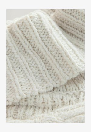 Gruby sweter z dzianiny w kremowym kolorze z prążkowaną fakturą i wypukłymi wzorami, wykonany z miękkiej włóczki, o przytulnym, grubym wyglądzie.