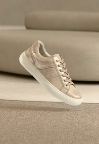 Μπεζ δερμάτινα αθλητικά παπούτσια με λεία επιφάνεια, στρογγυλή μύτη και σχέδιο με κορδόνια. Υφασμένα πλαϊνά διακοσμητικά στοιχεία και λαστιχένια σόλα.
