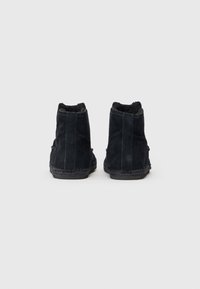Botines de ante negros con un acabado texturizado, paneles laterales elásticos y una suela cosida. El interior está forrado para mayor comodidad.