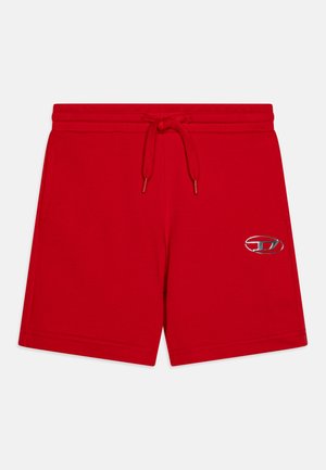 Rote Baumwollshorts mit einem elastischen Bund und Kordelzug. Mit einem metallischen Emblem am linken Bein. Glatte Textur, lässiges Design.
