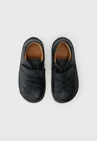 Μαύρα δερμάτινα παπούτσια με υφή, διαθέτουν δύο λουράκια με βέλκρο για ασφαλές κλείσιμο. Στρογγυλερή μύτη και επενδεδυμένο πάτο για άνεση.