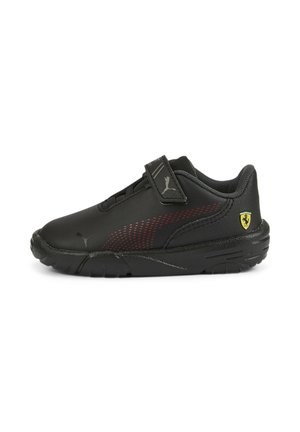 Chaussures de sport noires avec une tige synthétique lisse, des accents rouges, une bride auto-agrippante et une semelle en caoutchouc texturée. Logo Ferrari sur le talon.