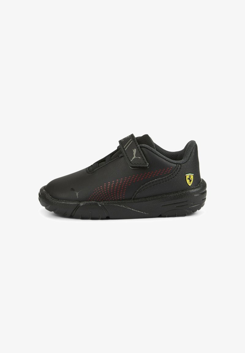 Chaussures de sport noires avec une tige synthétique lisse, des accents rouges, une bride auto-agrippante et une semelle en caoutchouc texturée. Logo Ferrari sur le talon.