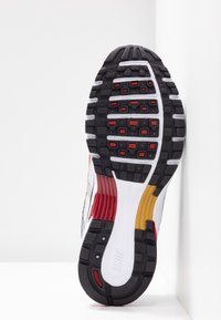 Sole Nike tenisky, s černou gumou, červenými akcenty, texturovaným vzorem, bílou mezipodešví a barevnými sekcemi v žluté a červené.