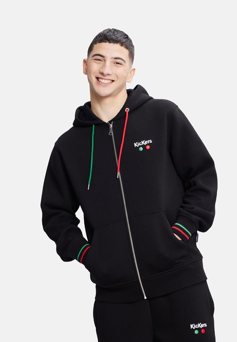 Felpa nera con zip realizzata in un misto cotone, dotata di un cappuccio con lacci verde e rosso, polsini a coste con strisce coordinate e dettaglio del logo.