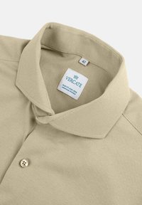 Beige polo shirt met een gestructureerde stof, slim fit ontwerp, knoopsluiting en een label met de tekst "VERCATE" met maat 42. Strijkvrij functie.