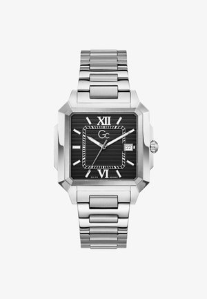 Kwadratowy srebrny zegarek na nadgarstek z czarną, żebrowaną tarczą, cyframi rzymskimi na godzinie 12 i 6, srebrnymi znacznikami, okienkiem daty na godzinie 3 oraz metalową bransoletą.