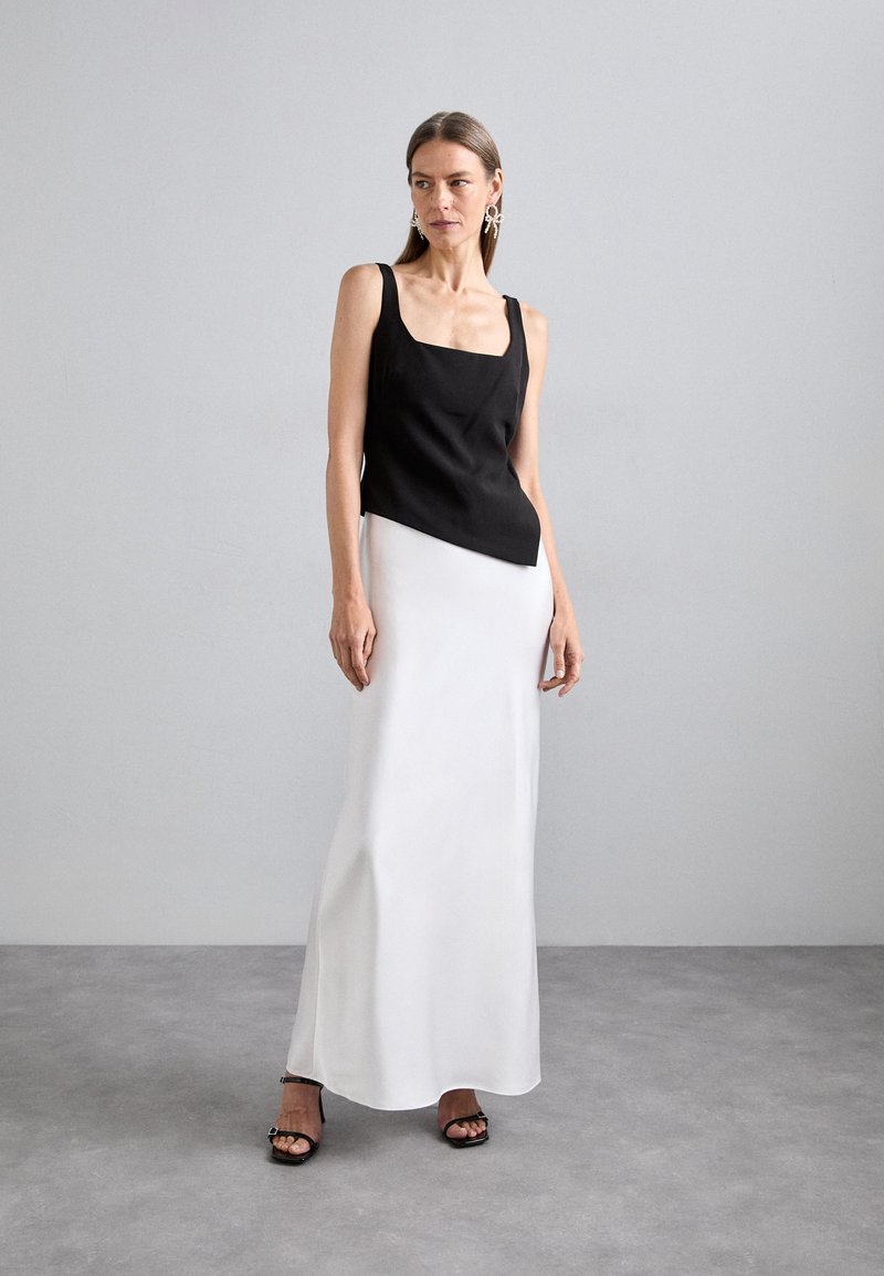 Black sleeveless top with a square neckline paired with a white satin maxi skirt. The outfit features a smooth texture and a modern design.