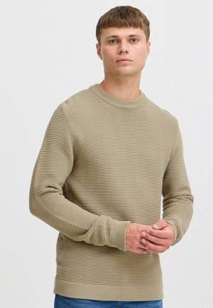 Beige ribbed knit sweater with a round neckline, long sleeves, and a textured pattern. Features fitted cuffs and hem.
