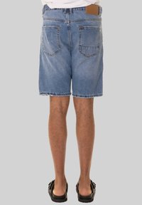 Shorts in denim di un blu chiaro, con un taglio classico, due tasche posteriori e un'etichetta in cuoio in vita. Finitura con orlo grezzo.