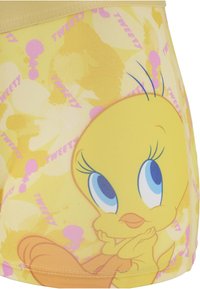 Tissu jaune avec un grand visage de Titi, yeux bleus, bec orange, queue, et texte récurrent « Tweety » en rose sur un fond jaune.