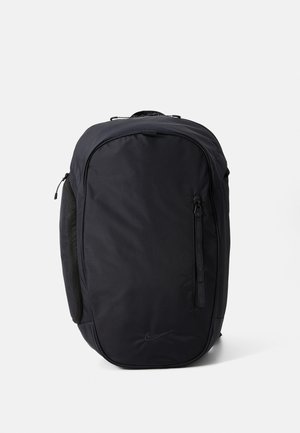 Black Nike backpack with a smooth, matte texture, a zippered side pocket, and a sleek, rounded design. Features a logo on the front.