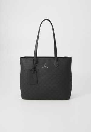 Black tote bag featuring embossed pattern, two long handles, a rectangular shape, and a tag with a logo detail. Made of durable material.