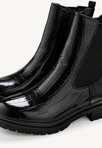 Bottes Chelsea en cuir verni noir avec un motif crocodile texturé, des panneaux latéraux élastiques et une semelle en caoutchouc noire robuste.