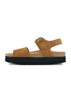 Brown suede open-toe sandal with cork footbed, adjustable buckle strap, and thick black ridged sole, side view on white background.